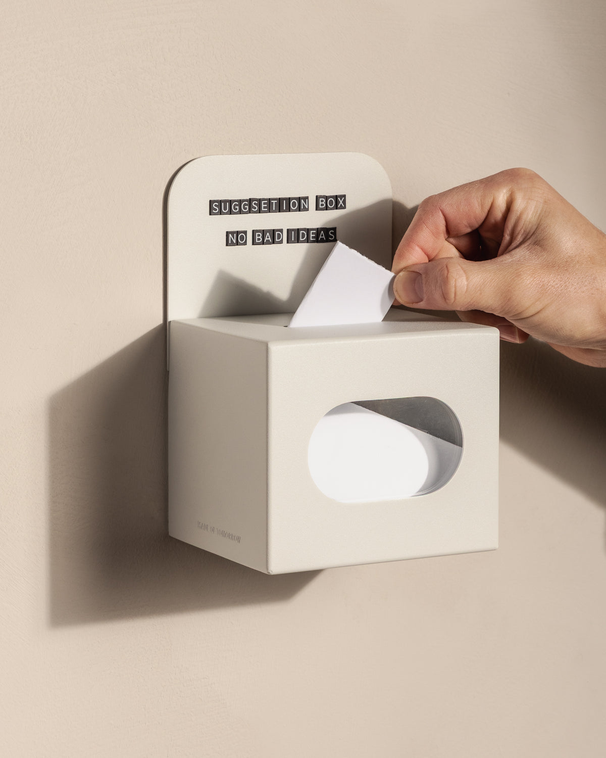 Customer posting a suggestion card into the wall-mounted white FOLD Tip Box